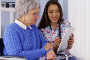 caregiver sharing tablet with elderly patient